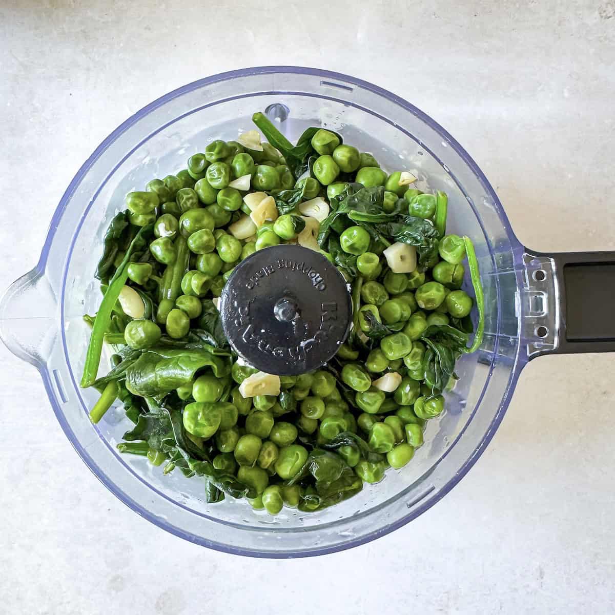green pasta sauce ingredients in a food processor before being blended.