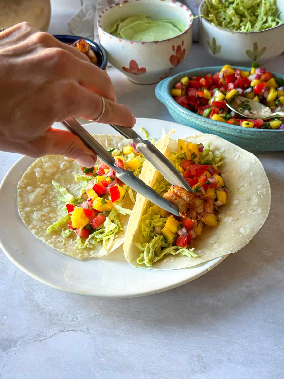 A hand assembling a shrimp taco.