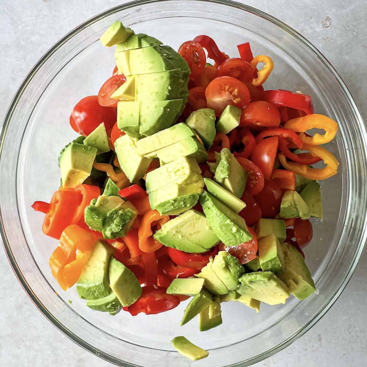 overhead view of cucumber pepper salad ingredients in a bowl..