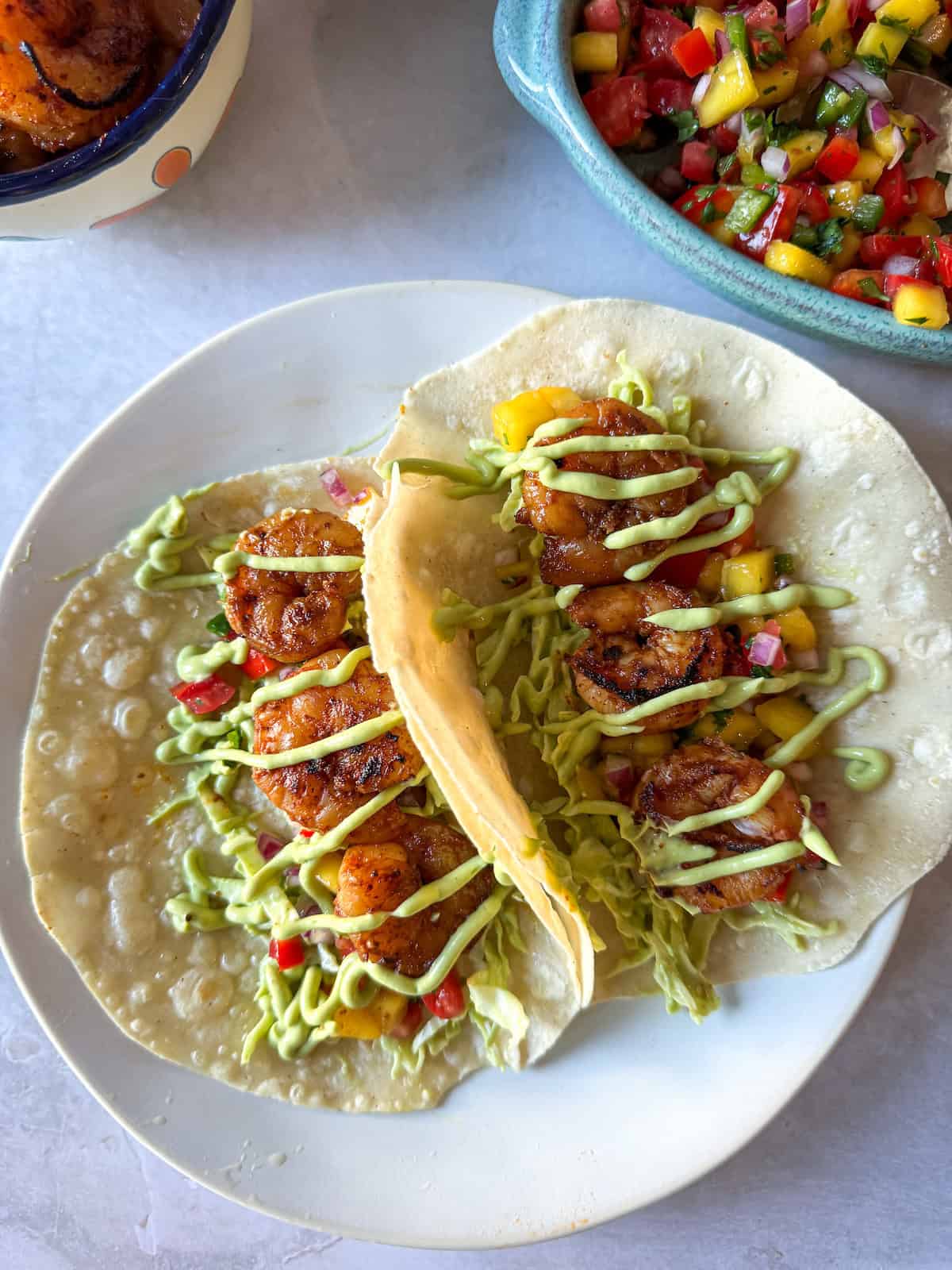 Shrimp tacos with avocado crema on top.