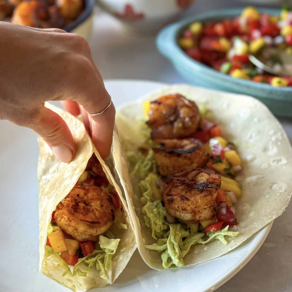 A human hand holding a shrimp taco.