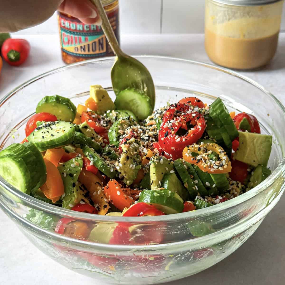 spoon tossing a cucumber pepper salad.