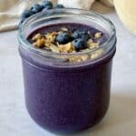 Blueberry smoothie without yogurt in a mason jar with granola and blueberries on top.