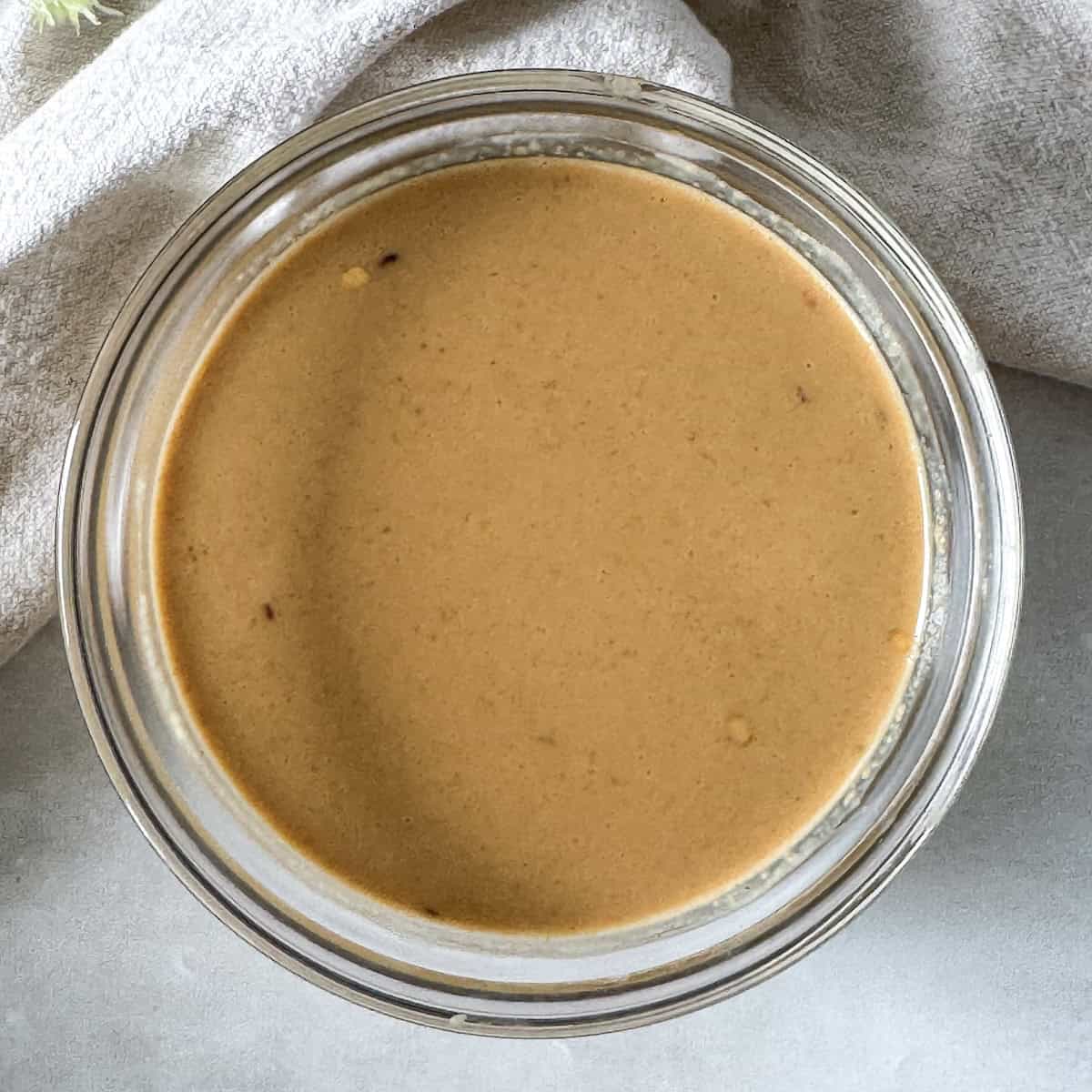 overhead view of peanut lime dressing in a glass bowl.