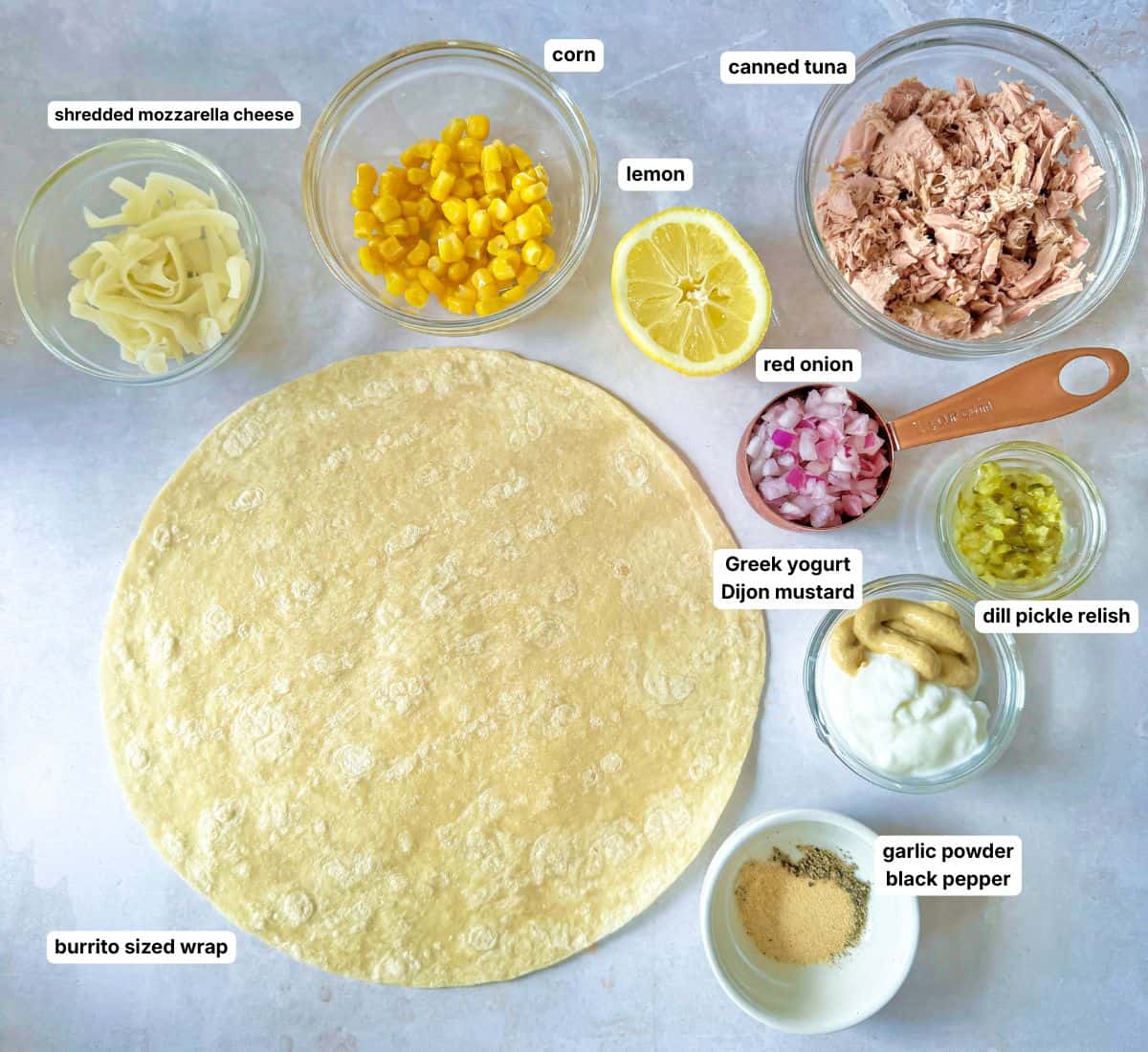 Ingredients for a tuna melt wrap in separate containers on a table labled.