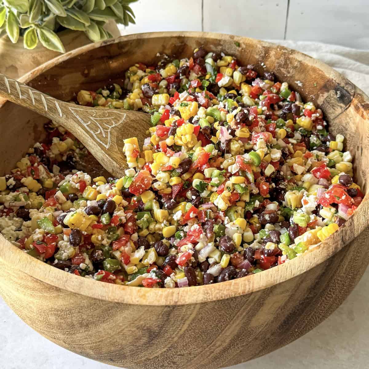 a wooden bowl with black bean and corn salsa in it.