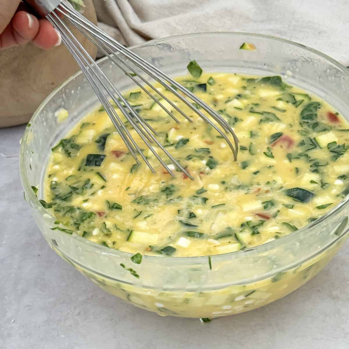 cottage cheese egg bake ingredients being mixed in a glass bowl.
