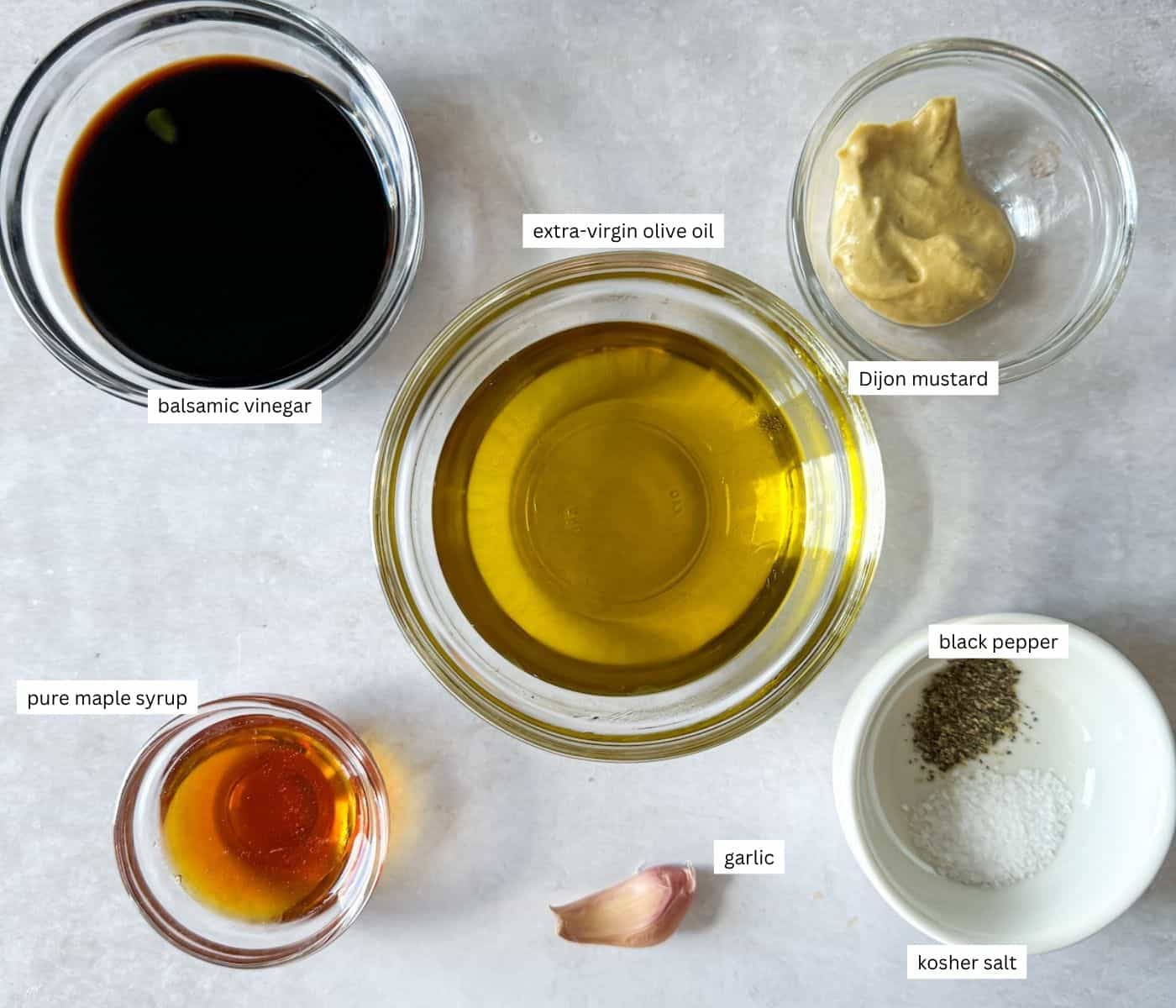 Ingredients for balsamic maple vinaigrette in individual containers on a table.