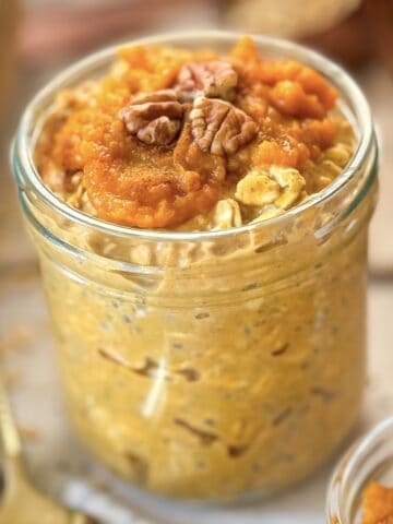 Pumpkin pie overnight oats in a mason jar with pecans on top.