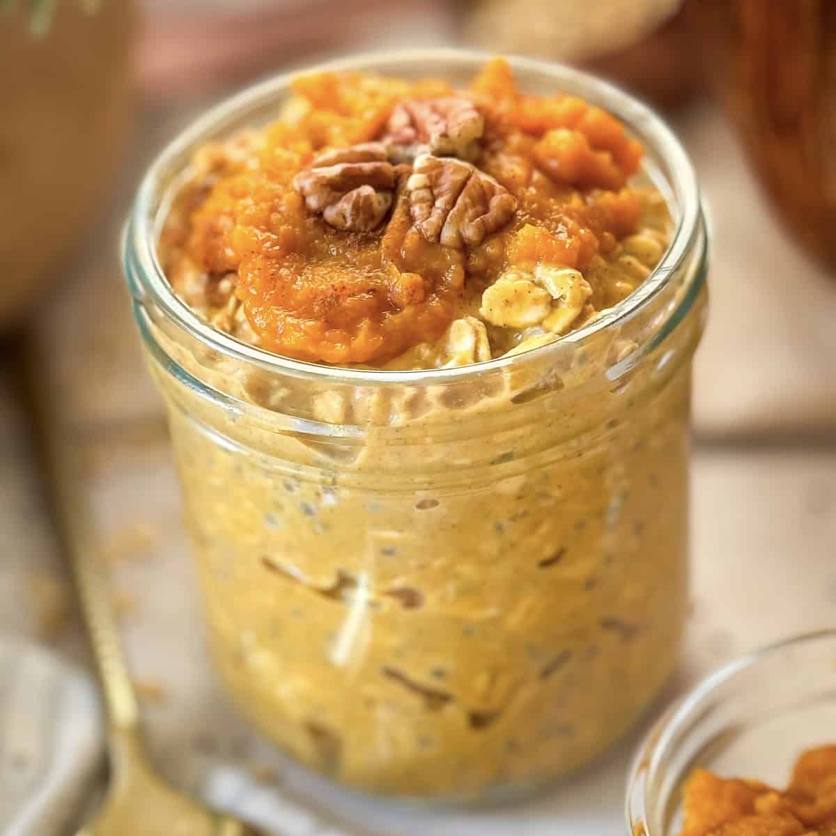 Pumpkin pie overnight oats in a mason jar with pecans on top. 