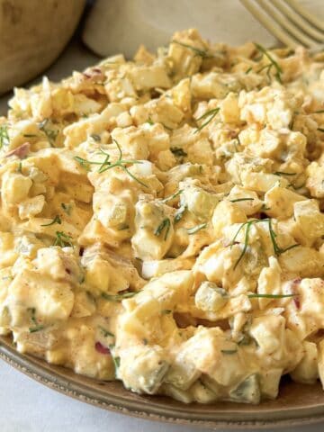 Dill pickle egg salad on a plate with a fork in the background.