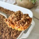 sweet potato casserole no marshmallows in a baking dish. A piece being held by serving utensil.