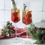 christmas ice cubes with prosecco and rosemary in champagne glasses on a table.