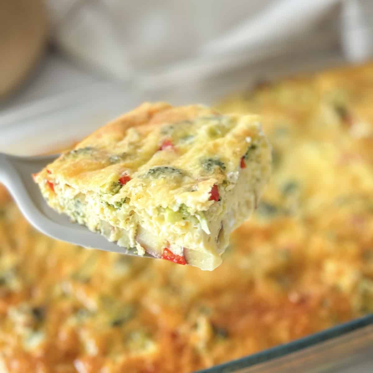 serving utensil holding a square of broccoli egg bake.