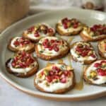 sweet potato bites with ricotta, pomegranate, and pistachios with honey on top.