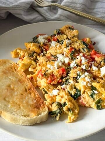 feta eggs scrambled on a plate with a slice of sourdough toast