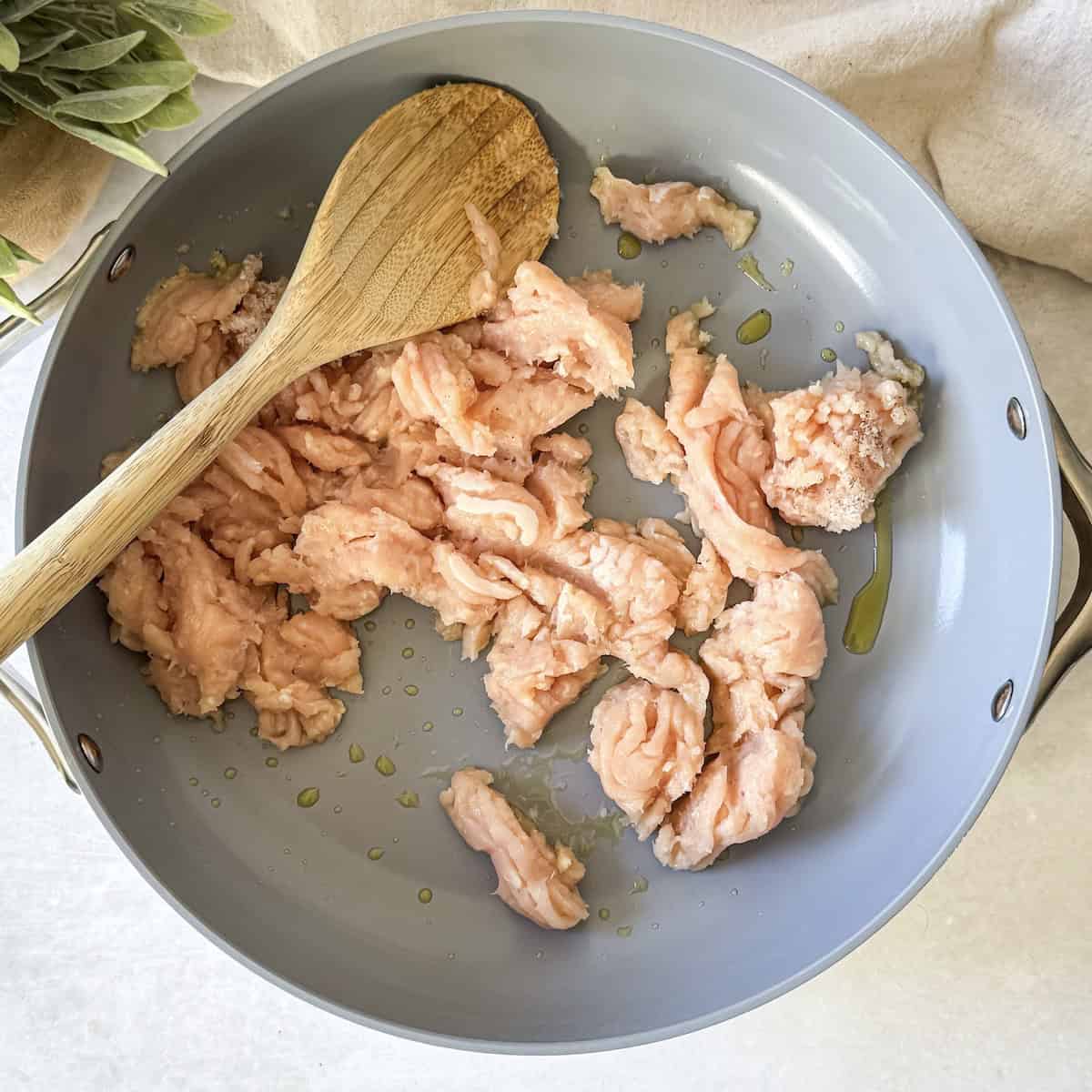 ground chicken in a pan with a wooden spoon.