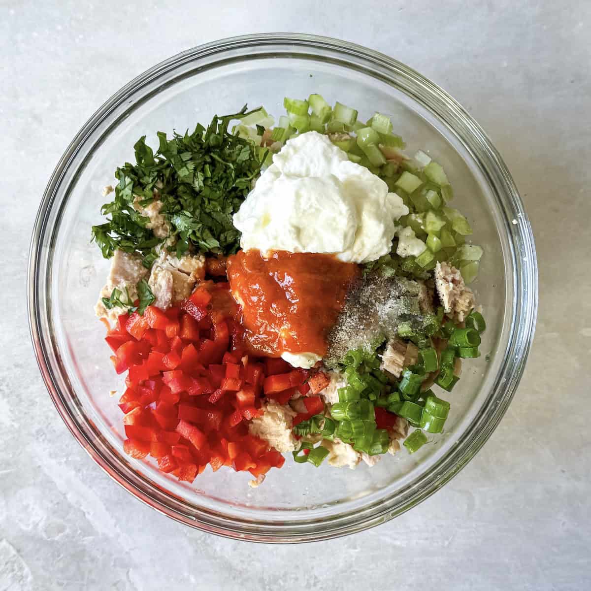 sriracha, Greek yogurt, and other dressing ingredients on top of vegetables and tuna.