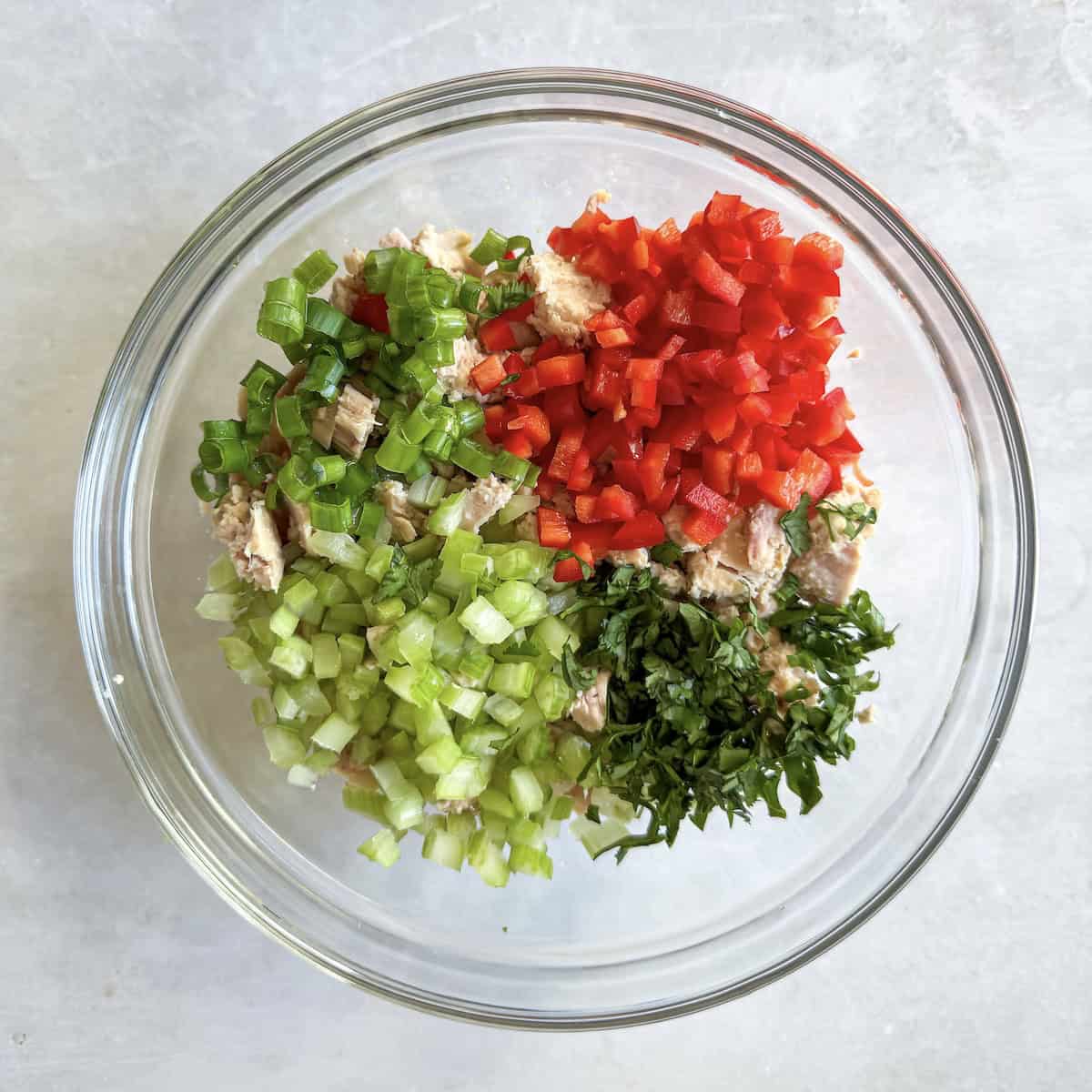 tuna, red peppers, celery, cilantro, and green onions in a glass bowl.