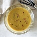 close up overhead view of hot honey mustard sauce with a whisk in the background