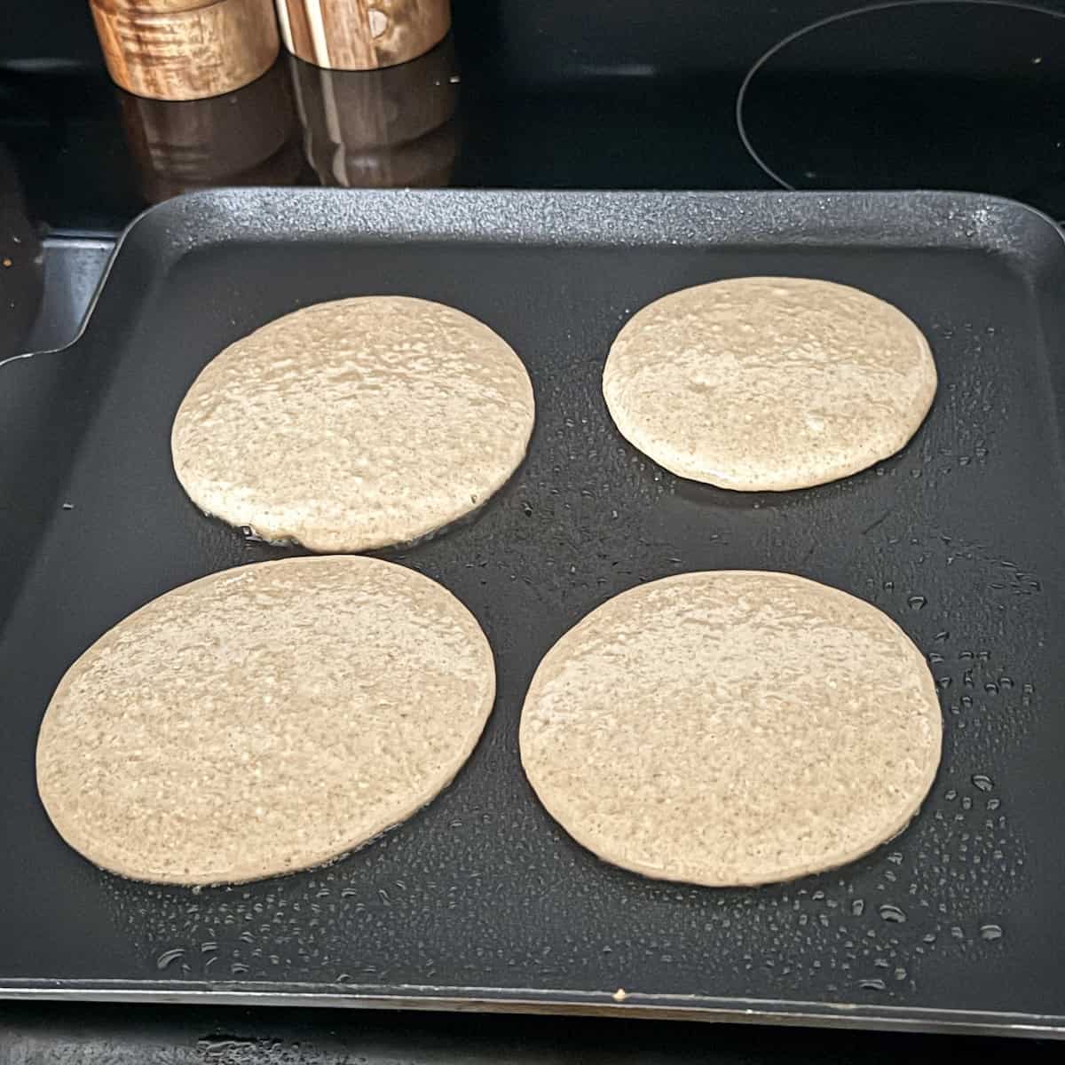 first side of banana pancakes on a griddle.