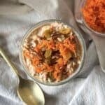 overhead view of carrot cake overnight oats with grated carrots and golden raisins on top and a spoon next to it.