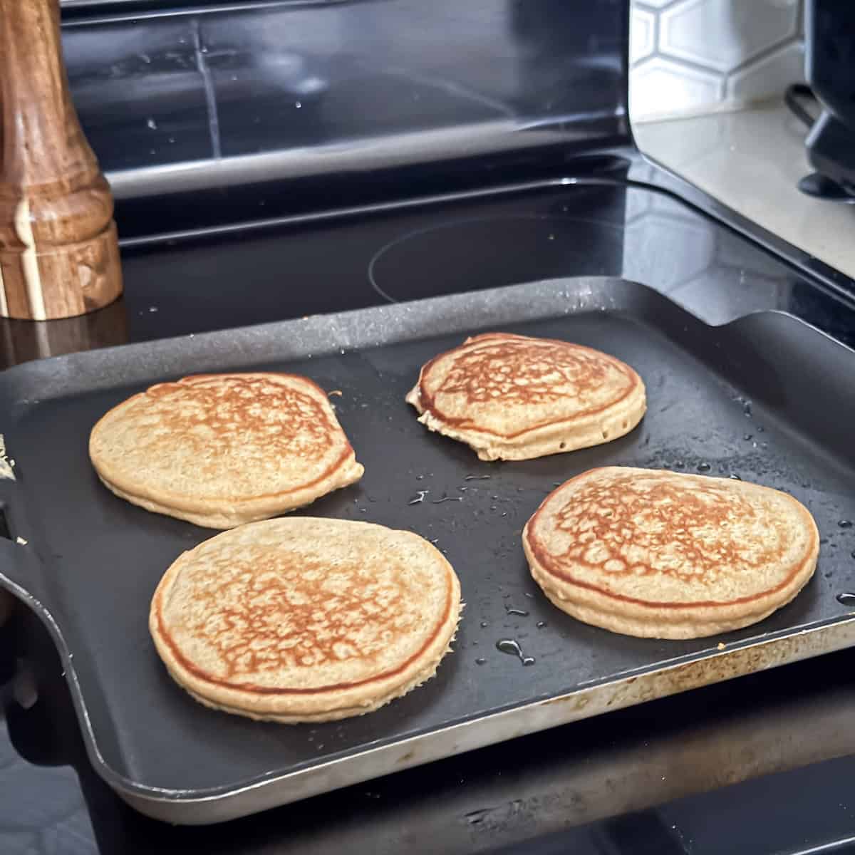 second side of banana oatmeal pancakes on a griddle.