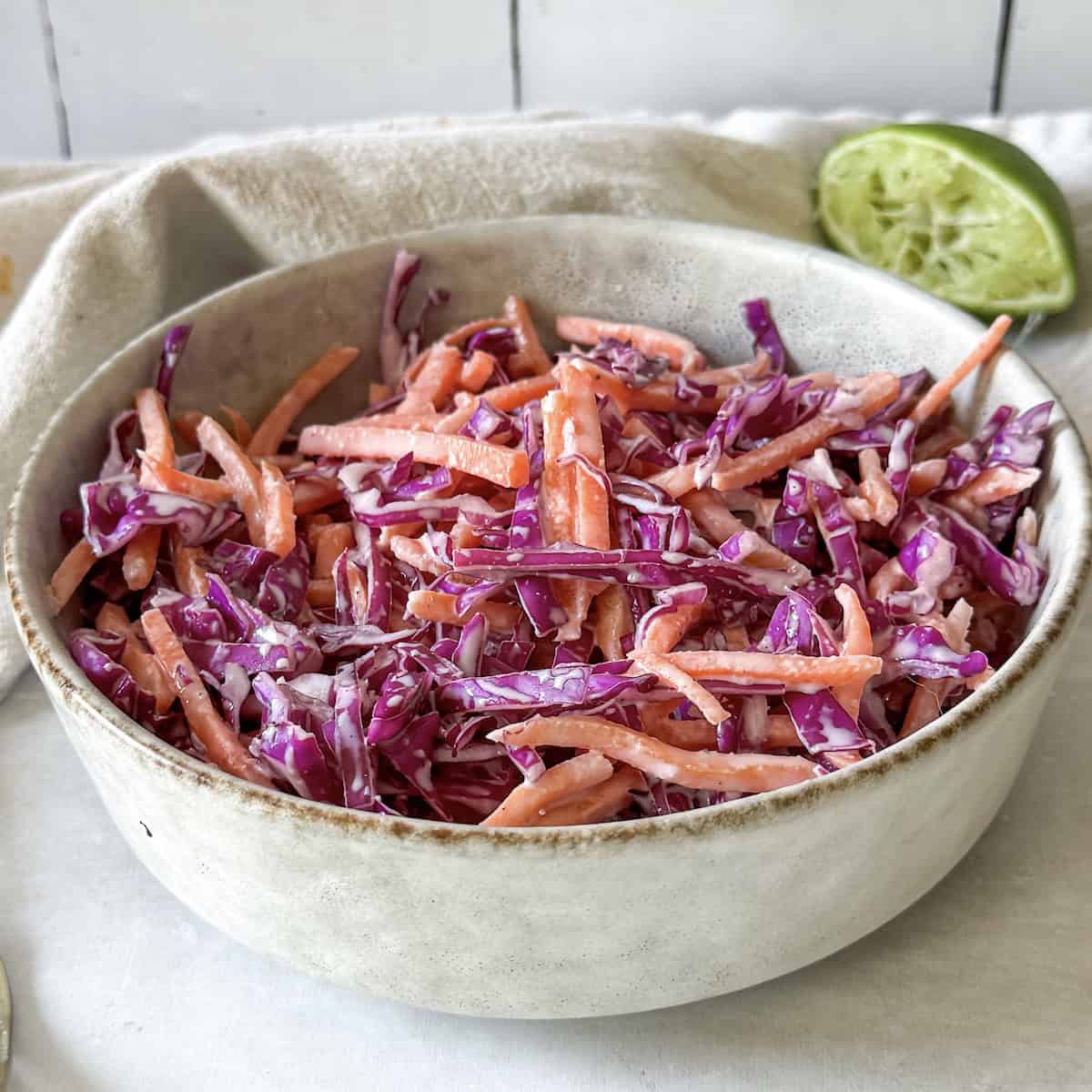 side angle view of purple cabbage coleslaw in a bowl.