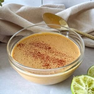 southwest salad dressing in a glass bowl with limes behind it. and a spoon.