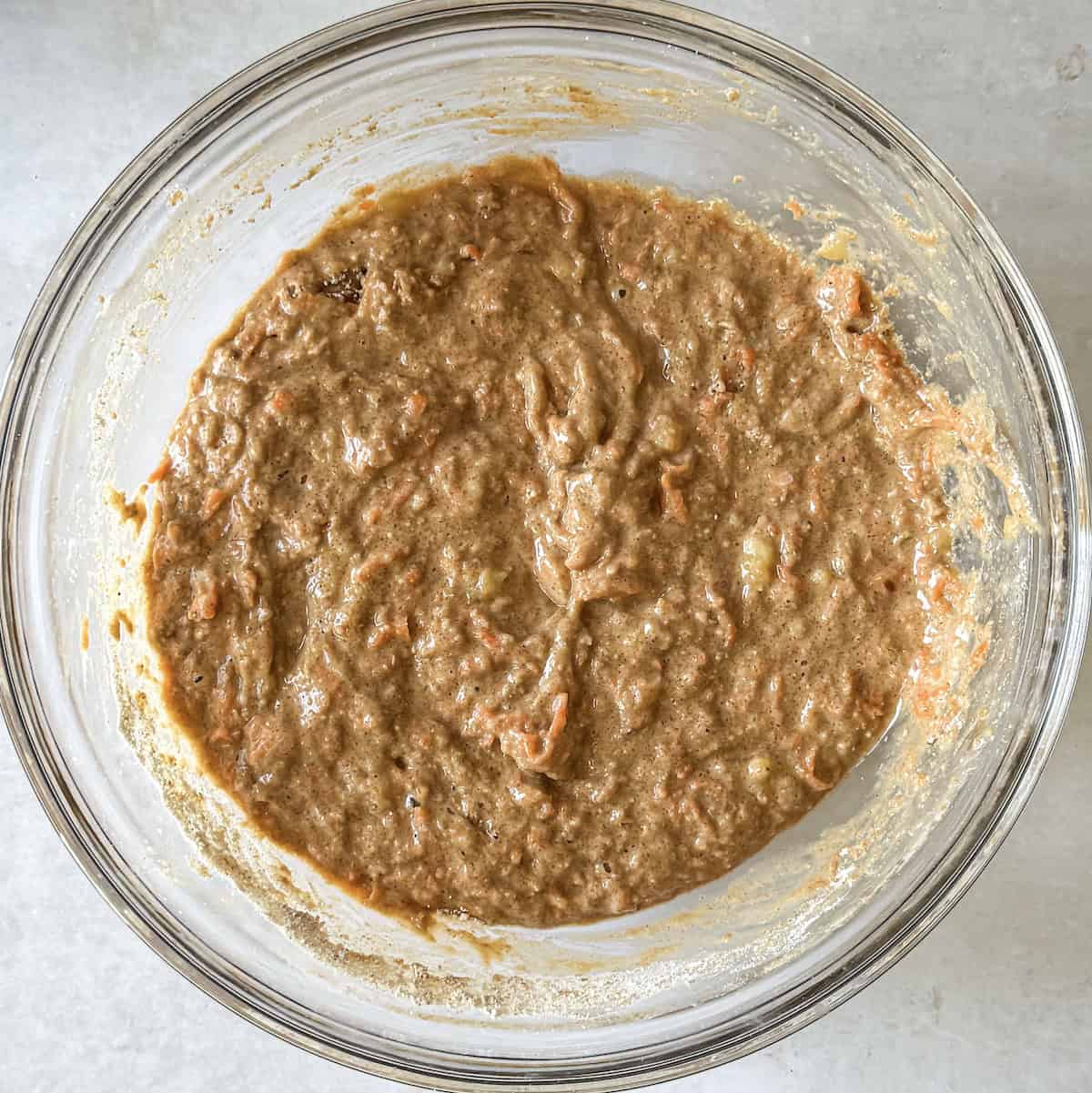 carrot and banana muffin batter in a glass bowl.