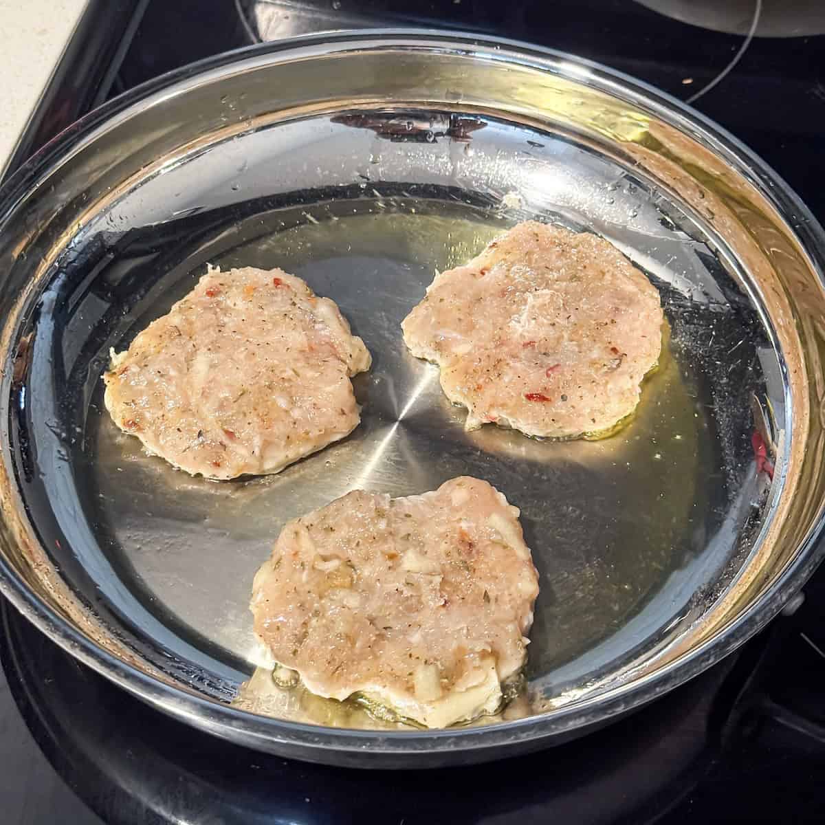 chicken breakfast sausage cooking in a stainless steel pan.
