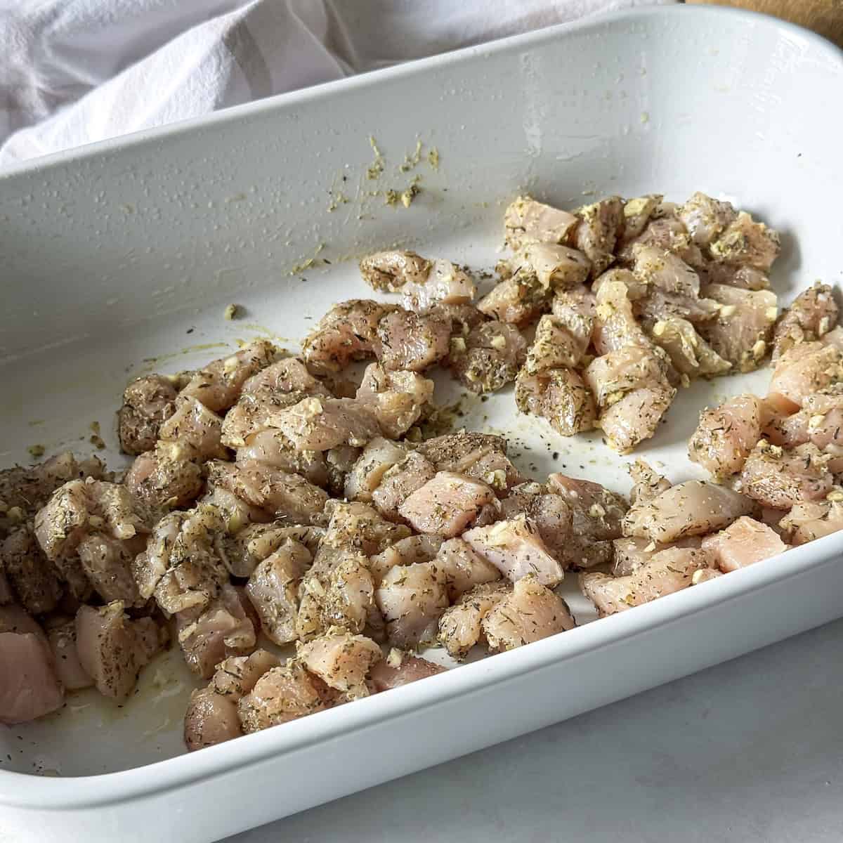 cubed chicken breast with seasonings in a baking dish.