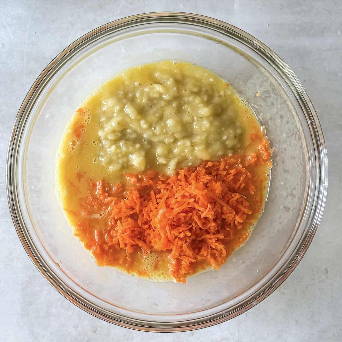 mashed banana and carrots in a glass bowl.