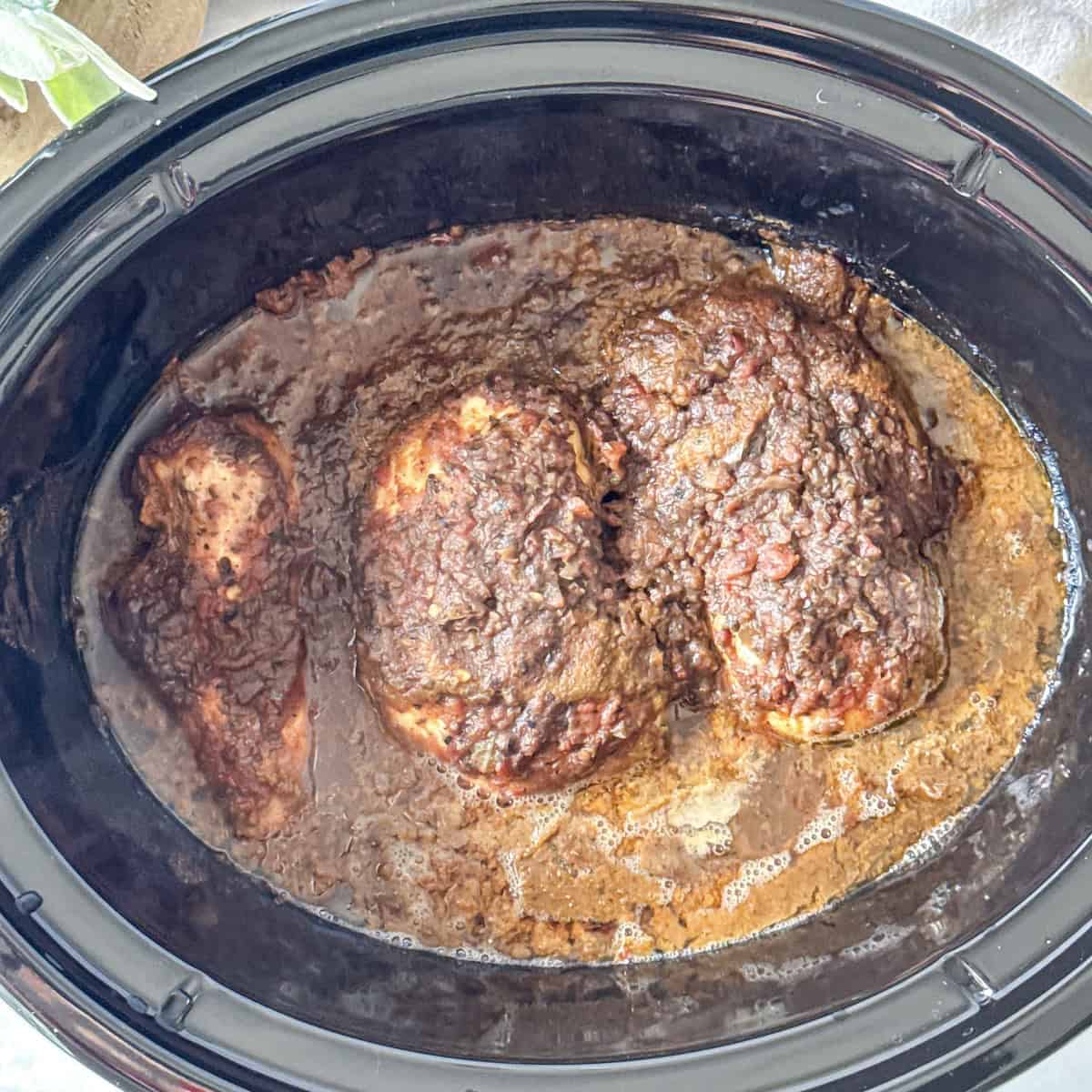 overhead view of chicken with salsa on top in a slow cooker.