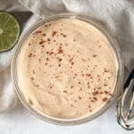 overhead view of dressing for mexican street corn salad in a glass bowl on a table.