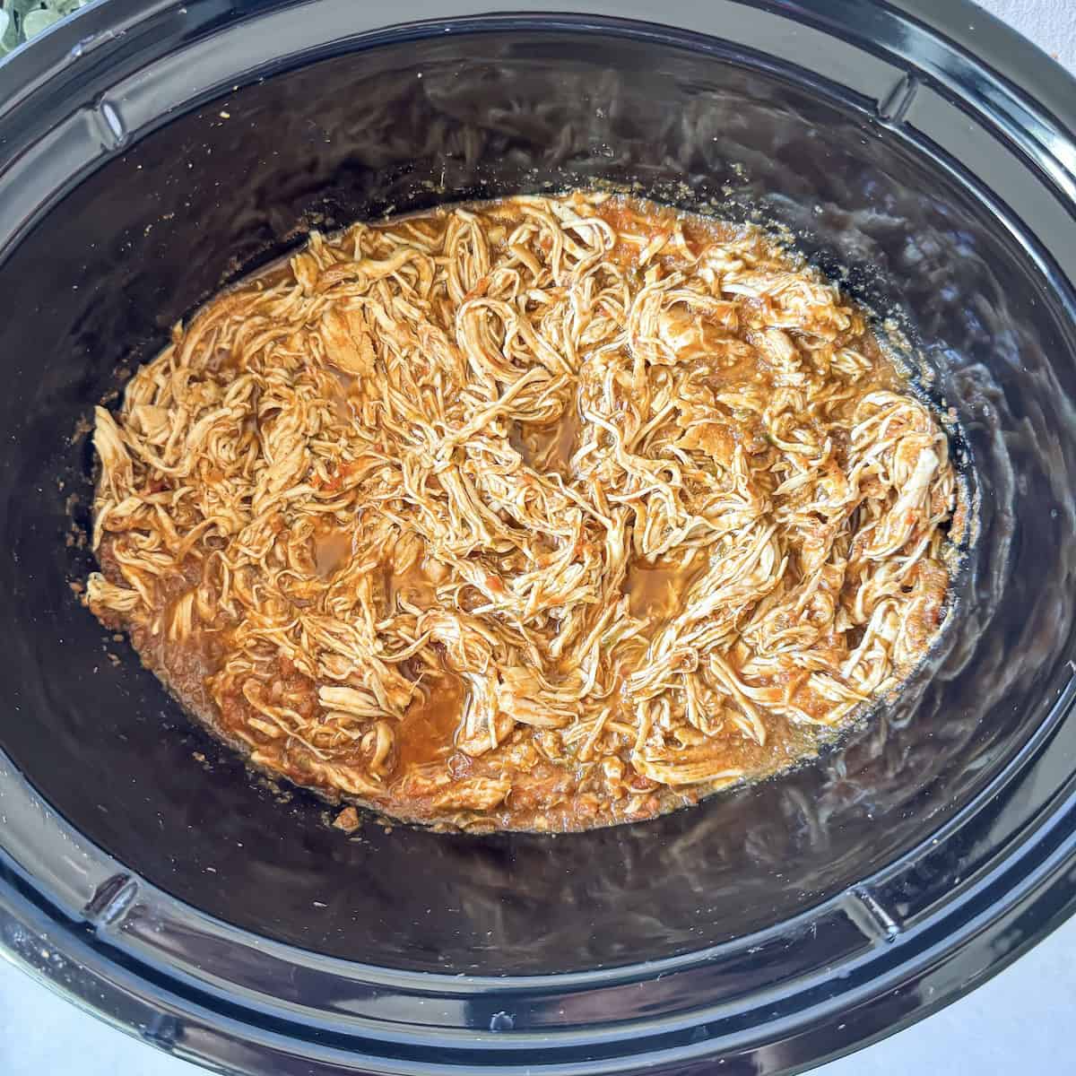 shredded chicken with salsa in a slow cooker.