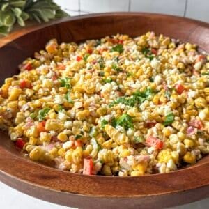 side view of mexican steeet corn salad in a wooden bowl.