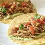 side view of slow cooker chicken tacos with salsa with cherry tomatoes on top.