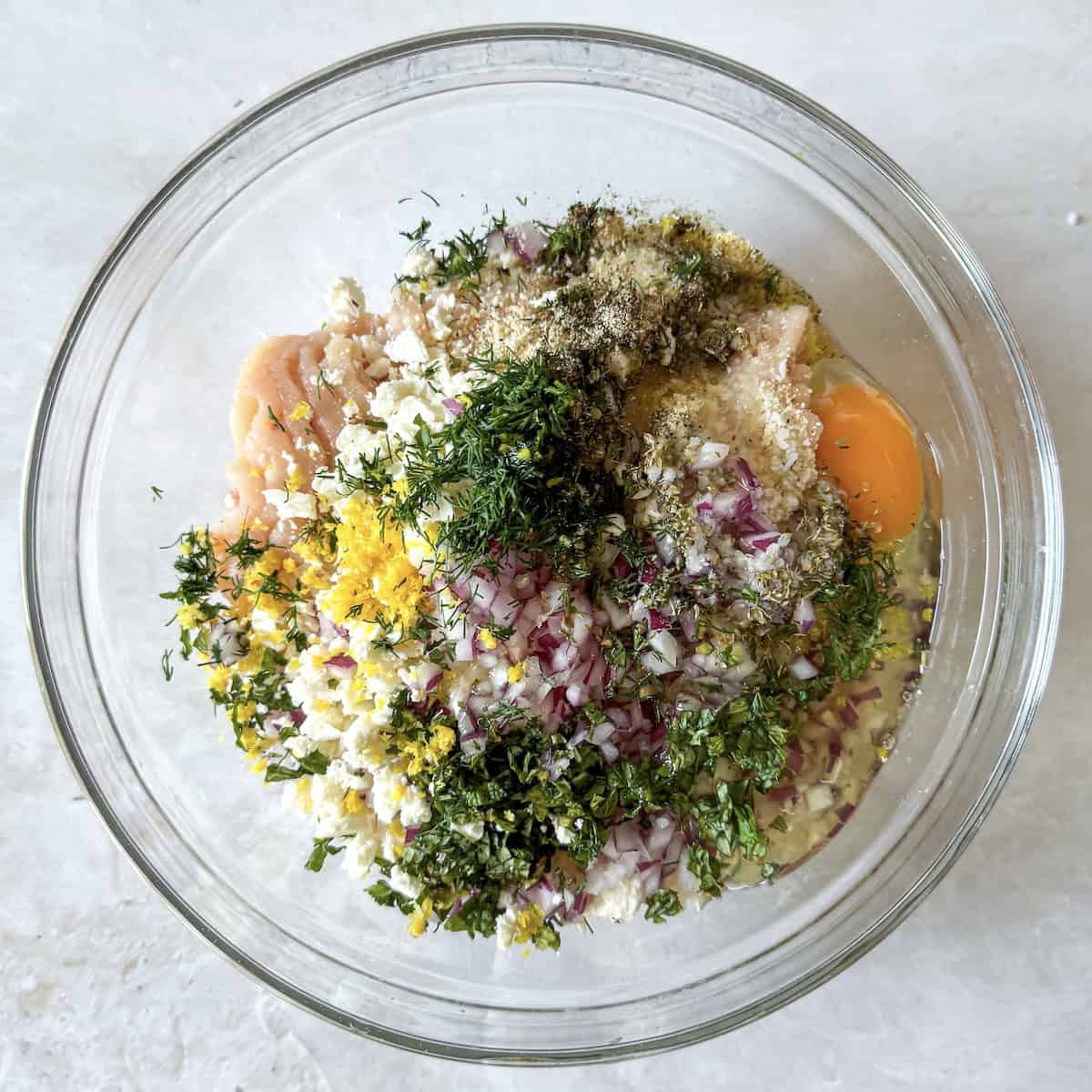 greek chicken meatball ingredients in a glass bowl overhead view.