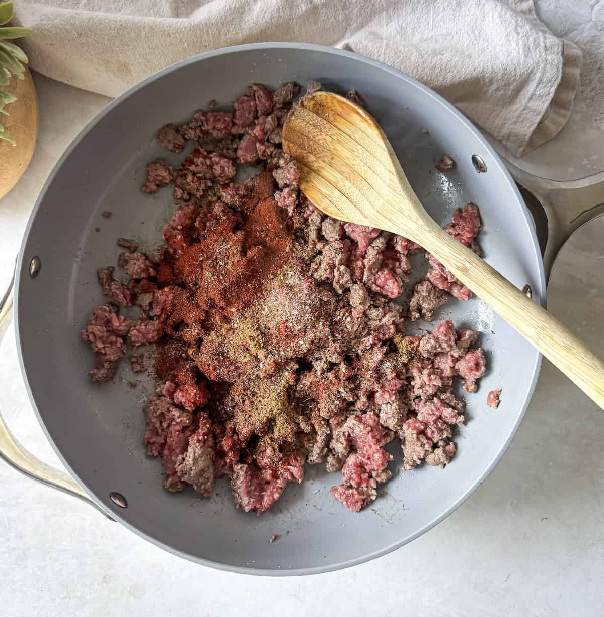 ground beef in a skillet with a wooden spoon