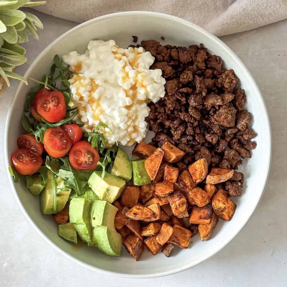 hot honey ground beef bowl with cottage cheese and sweet potatoes in a bowl overhead view.