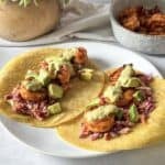 hot honey shrimp tacos with salsa on top on a plate.