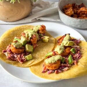 hot honey shrimp tacos with salsa on top on a plate.