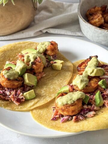 hot honey shrimp tacos with salsa on top on a plate.