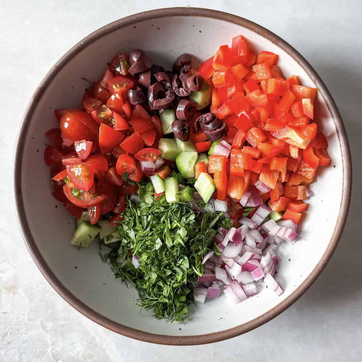 ingredients for cucumber and tomato salad with feta before feta and dressing have been added.
