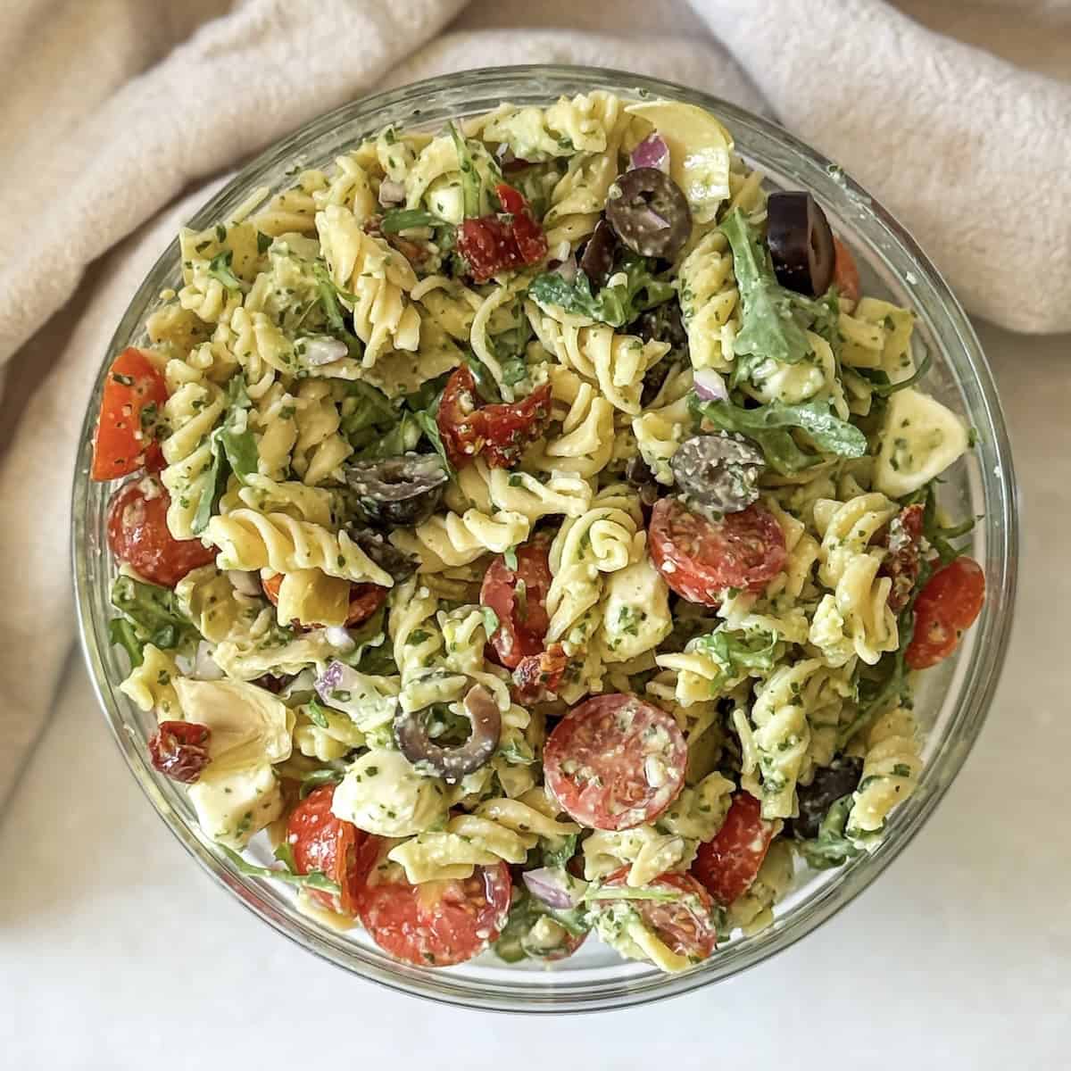 pesto pasta salad with sundried tomatoes in a glass bowl overhead