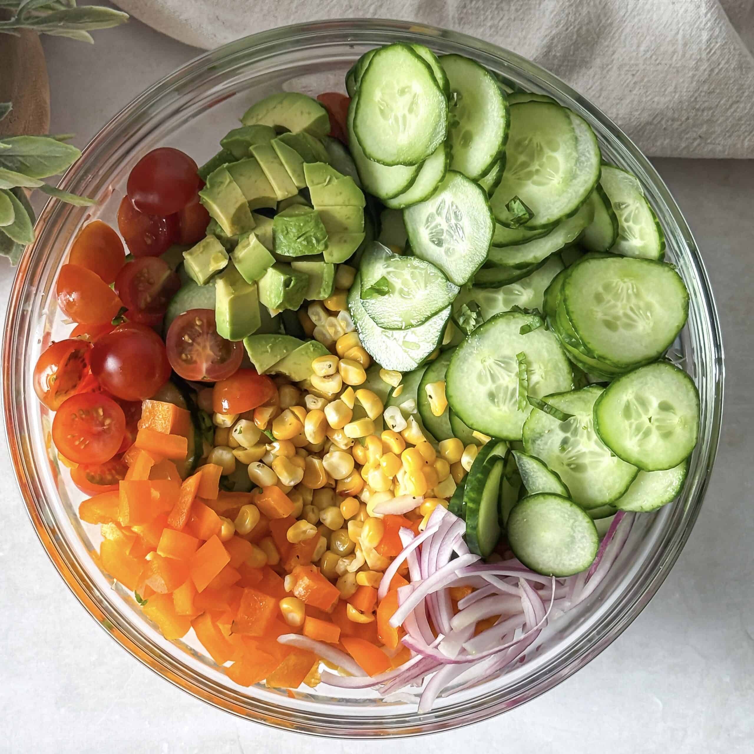 overhead view of corn cucumber salad ingredients in a glass bowl without dressing.