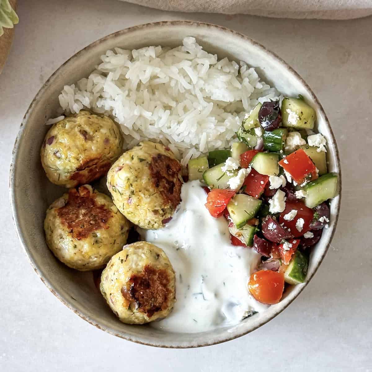 overhead view of greek chicken meatball bowl with yogurt dill sauce.