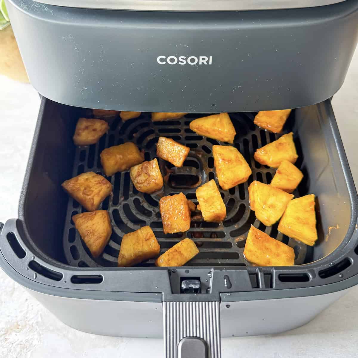 pineapple chunks in an air fryer basket side view