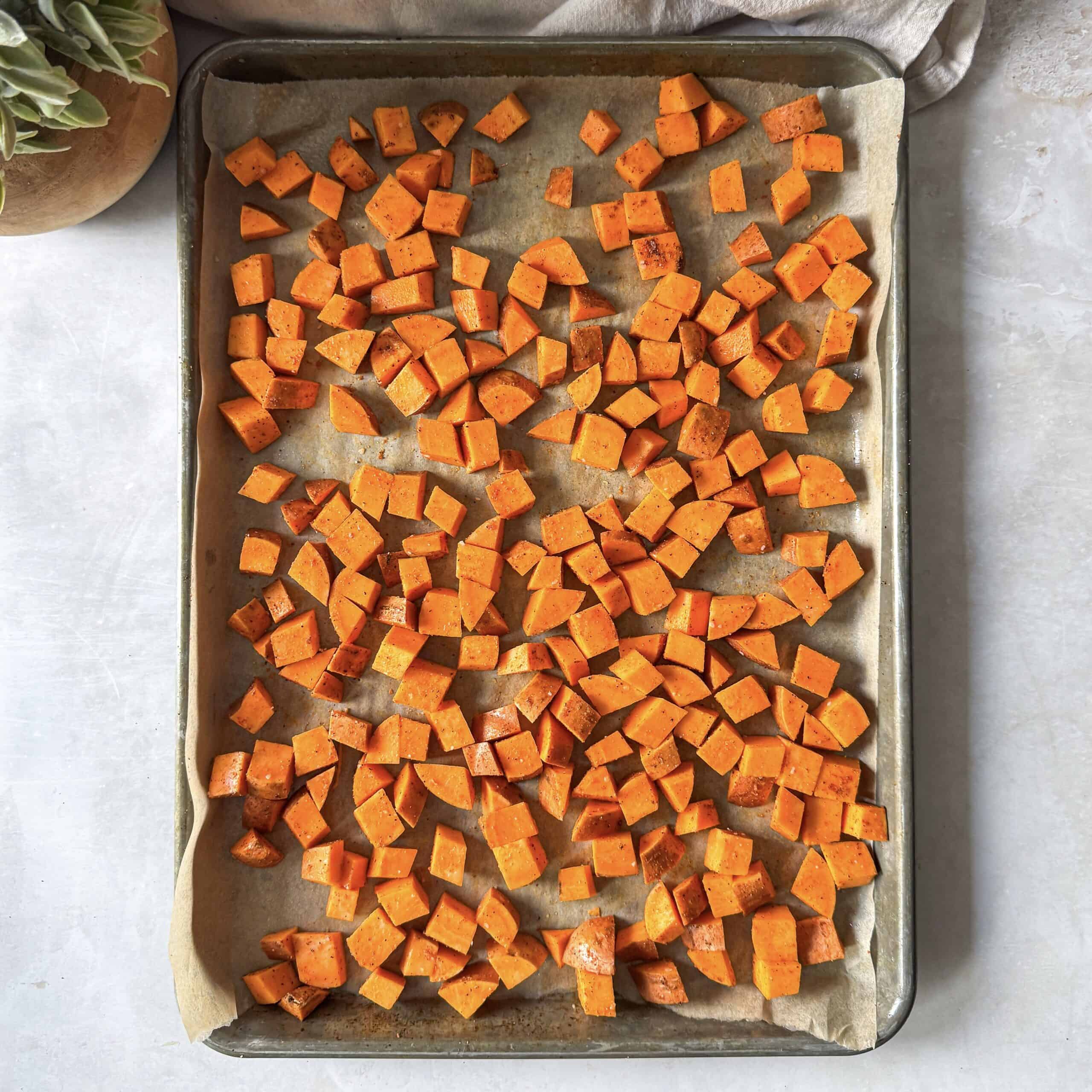 sweet potatoes with seasoning on a baking sheet.